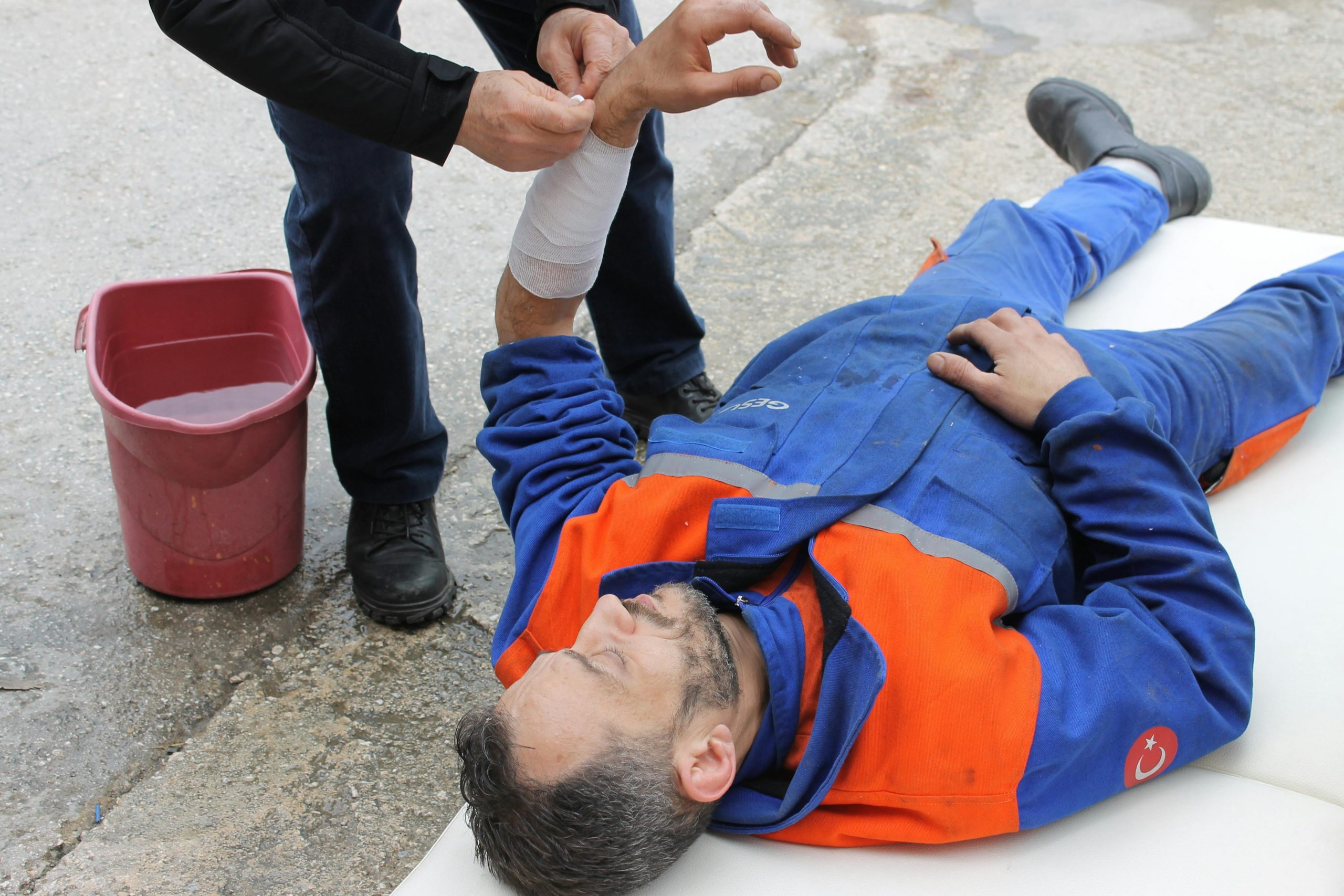 paramedic helping an injured worker lying on the ground